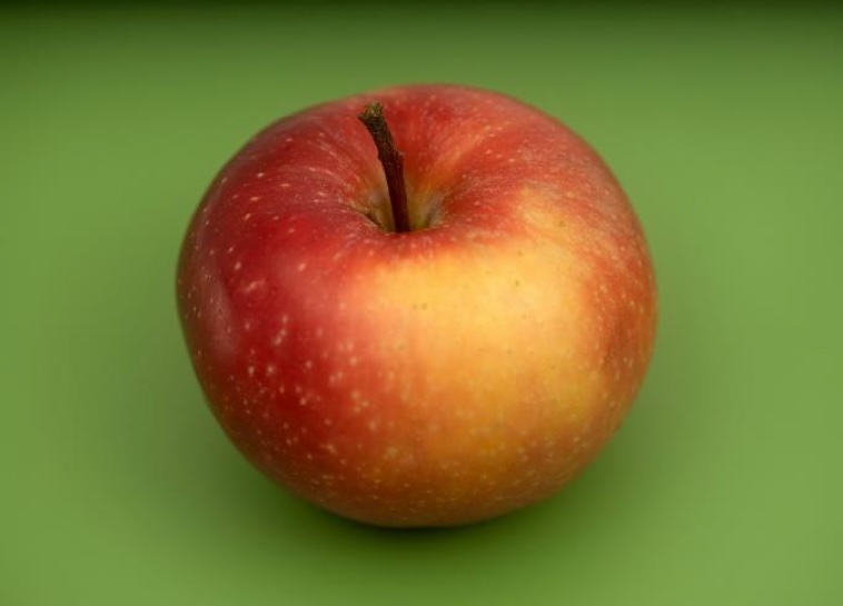 Photograph of a red apple on a green background